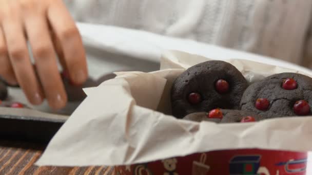 Hand neemt chocolade koekjes met cranberries uit een pan — Stockvideo