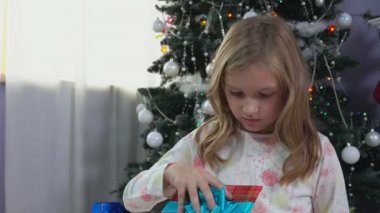 Küçük kız Noel ağacı yakınındaki bir Noel hediyesi verdi