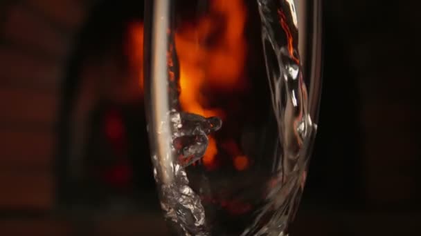 Champagne hälls i ett glas på en bakgrund av brand — Stockvideo