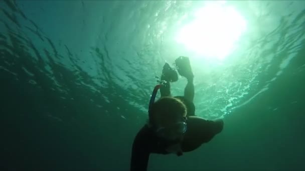 Buceador nada sobre un arrecife de coral en la luz del sol — Vídeo de stock
