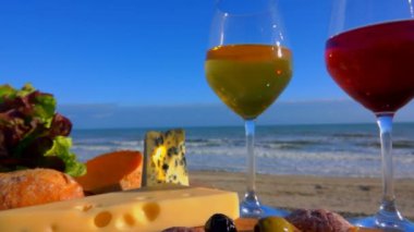 Romantik piknik Fransız peynir ve beyaz şarap ile Atlantik kıyısında. Hareket kamera pan. Bir bardak şarap güneş ışığı