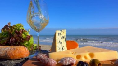 Romantik piknik Normandy peynir ve aperatif Atlantic Ocean Surf önünde ahşap bir gemide. Beyaz şarap bir bardak şarap dökülür