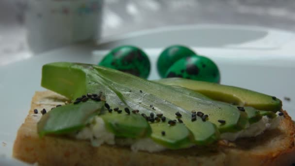 Sandwich mit Avocado bestreut mit schwarzem Sesam — Stockvideo