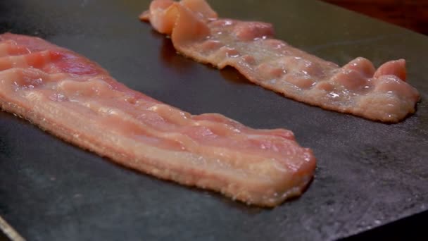 Duas tiras de bacon assobiando e fritando na grelha — Vídeo de Stock