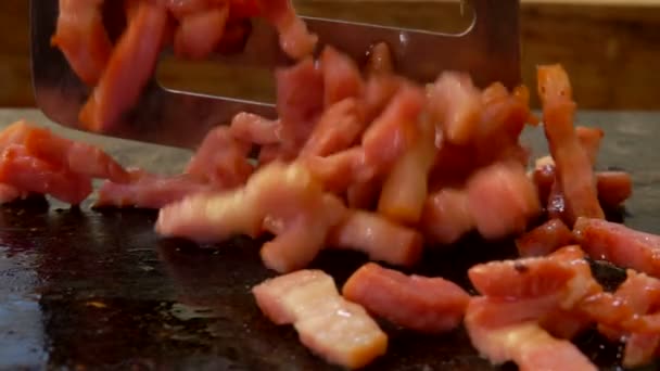 Metal spatula turns the diced bacon on the grill — Stock Video