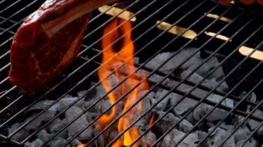 Şef biftek ızgara ızgara maşa kullanarak koyar