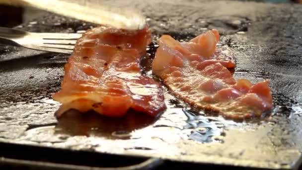 Hostess turns bacon with metal tongs — Stock Video