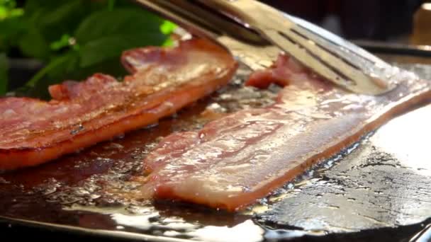 Cook turns bacon with metal tongs — Stock Video