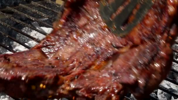 Hostitelka se změní steak pomocí kleští na grilovací rošt. — Stock video