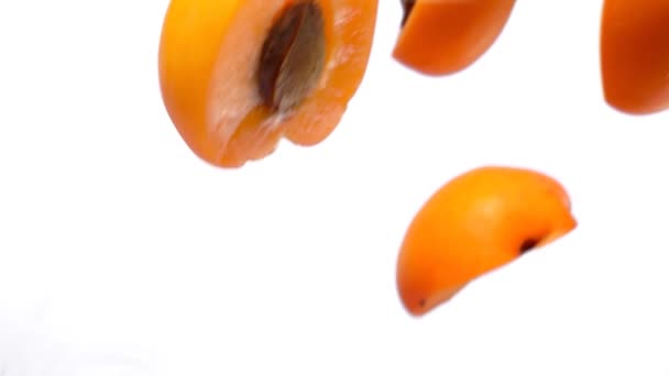 Половинки спелых абрикосов летают на белом фоне i — стоковое видео