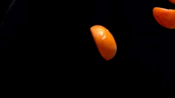 Половина спелых абрикосов летит на черном фоне — стоковое видео