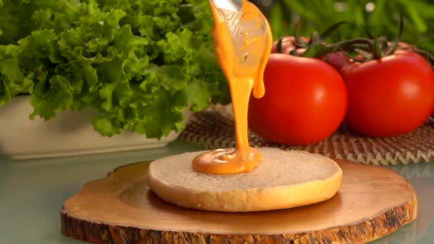 Löffel schmiert die Sauce auf ein Hamburger-Brötchen — Stockvideo
