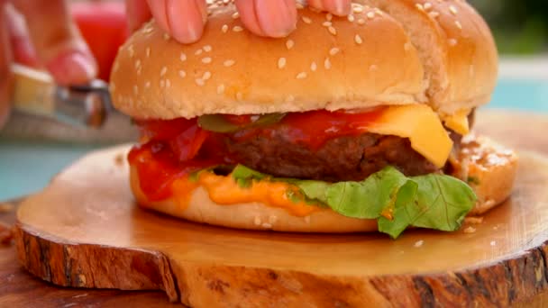 Mes snijdt in de helft van een heerlijke hamburger — Stockvideo