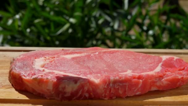 Koření se vrhne na Vepřový steak na dřevěném prkénku — Stock video