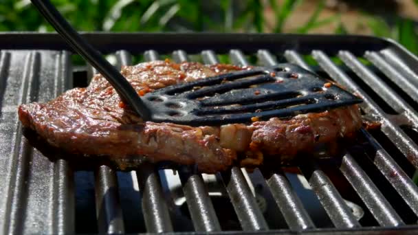 Steak is pressed by kitchen spatula to the grill — Stock Video