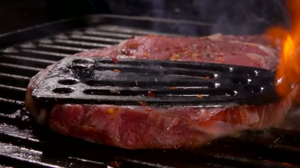 Steak wird mit dem Küchenspachtel auf den Grill gepresst — Stockvideo