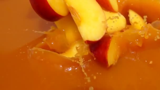 Slices of peach fall into juice — Stock Video
