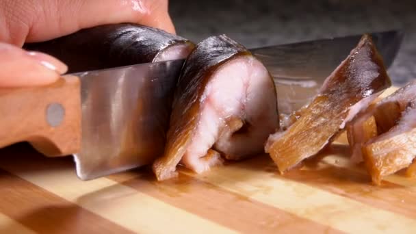 Хозяйка разрезает копченого угря на порции — стоковое видео