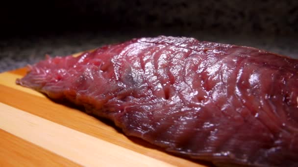 Salt faller på rå tonfisk som ligger på en bräda — Stockvideo