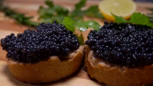 El caviar negro sobre los trozos blancos del pan se encuentra sobre la tabla — Vídeo de stock