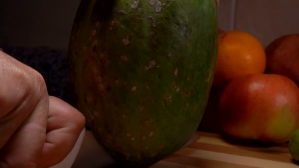 El cuchillo corta la papaya por la mitad en una tabla de bambú — Vídeo de stock