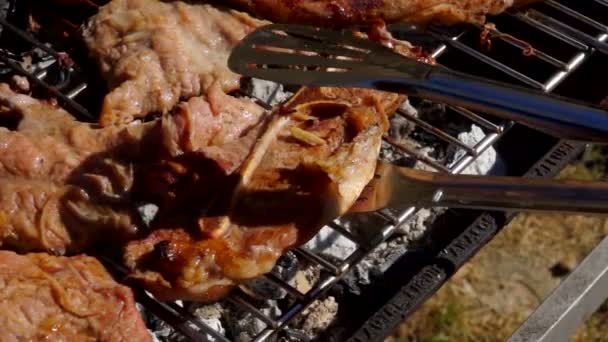 Cook lägger lammstek med en metall tång — Stockvideo