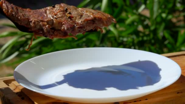 Koch legt das fertige Steak auf einen weißen Teller — Stockvideo