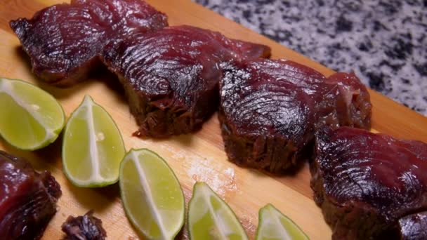 Pieces of salted tuna and lime are lying on a board — Stock Video