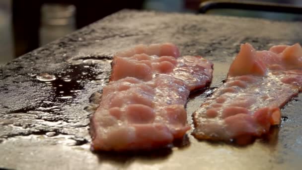 Twee bacon reepjes sissen en frituren op de grill — Stockvideo