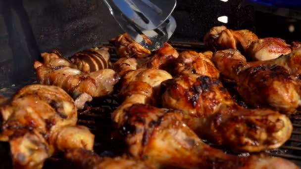 Chicken legs and wings turned with metal tongs — Stock Video