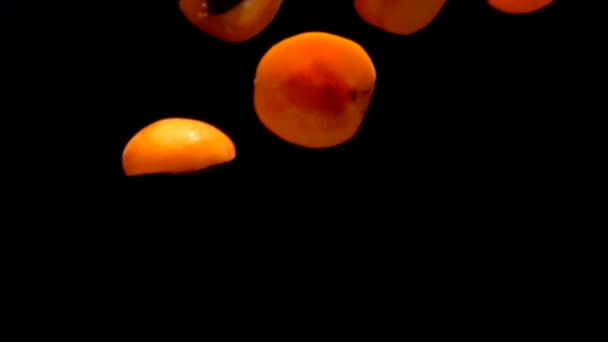 Helften rijpe abrikozen vliegen op een zwarte achtergrond — Stockvideo