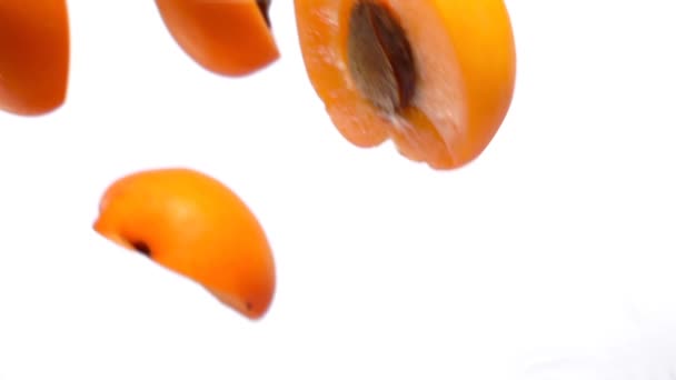Halves ripe apricots fly on white background i — Stock Video