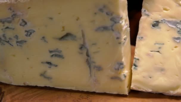 Trozo de queso cortado con moho azul cae sobre una tabla — Vídeos de Stock