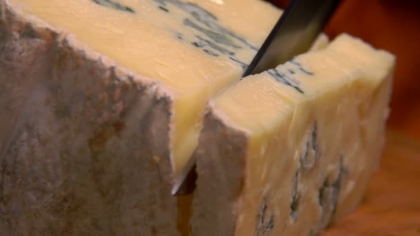 Нарізаний шматок сиру з блакитною цвіллю падає на дошку — стокове відео