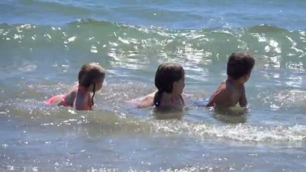Kinderen liggen in het water aan de lijn van de branding — Stockvideo