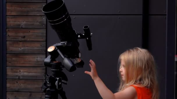 小さな女の子は望遠鏡を通して空を調べる — ストック動画