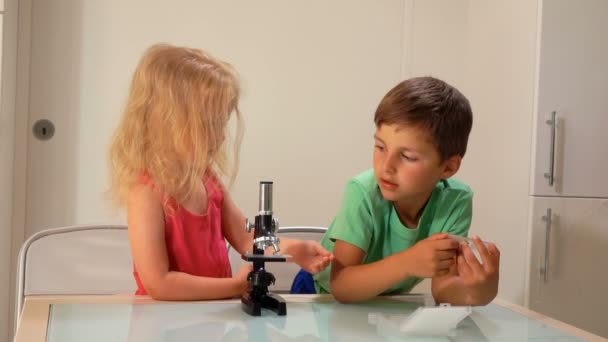 Kleine jongen handen een Microscoop dia naar het meisje — Stockvideo