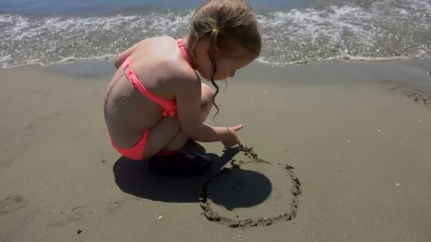 Girl draws her hands the sun on the sand — Stock Video