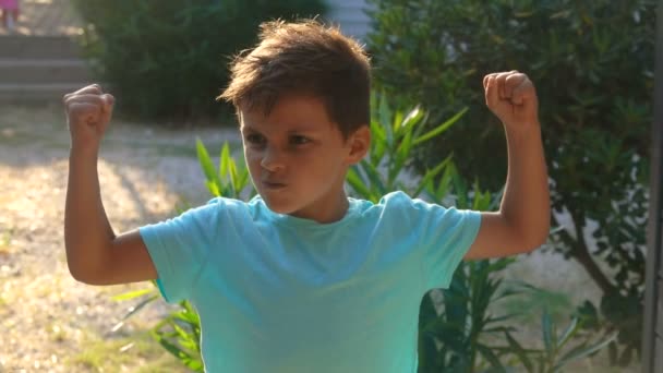Menino de camisa azul mostrando músculos — Vídeo de Stock