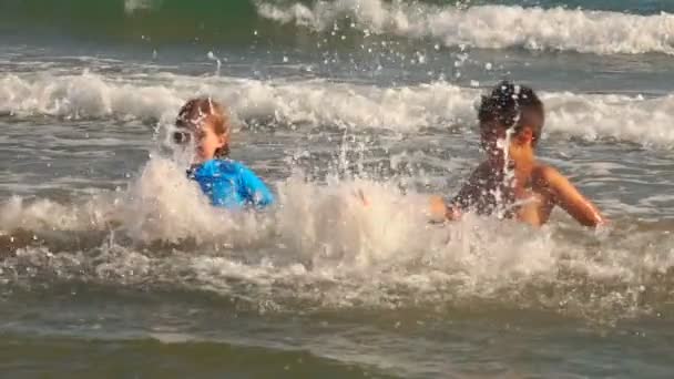 Gelukkig meisje en jongen in een blauw overhemd schoppen het water — Stockvideo