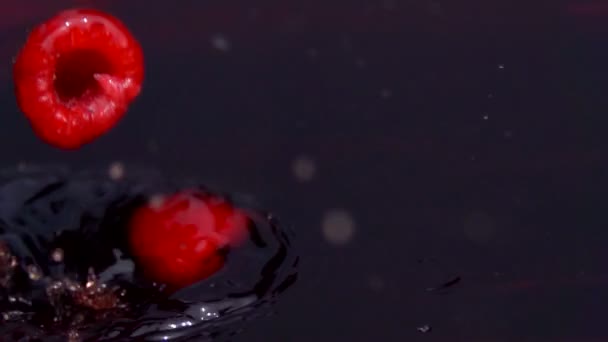 Framboises rouges mûres tombent dans le jus — Video