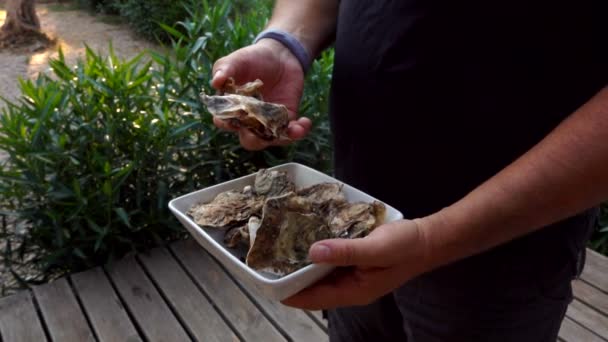 El hombre recoge una ostra en un plato blanco — Vídeos de Stock