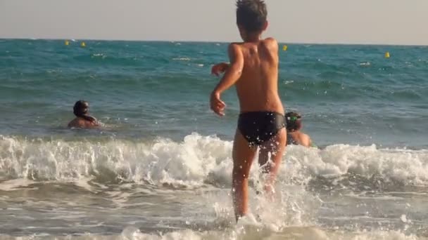 Šťastný teenager, skákající na vlnách — Stock video