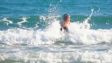 Lttle çocuk bir sörf tahtası üzerinde dalgalar atlıyor