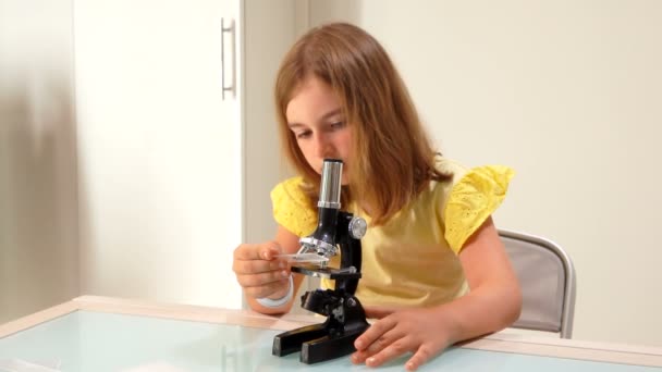 Girl inserts a glass slide into the microscope — Stock Video