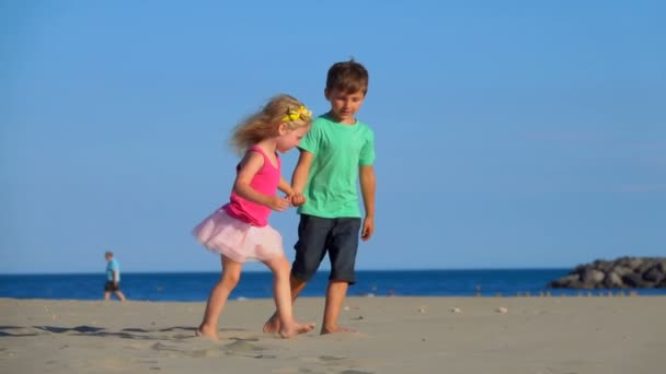 Niño y niña caminan por la playa — Vídeo de stock