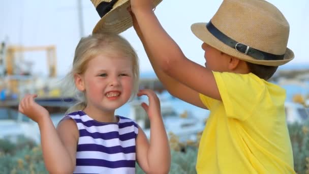 Pequeño niño ayuda a vestir a un sombrero de niñas — Vídeos de Stock