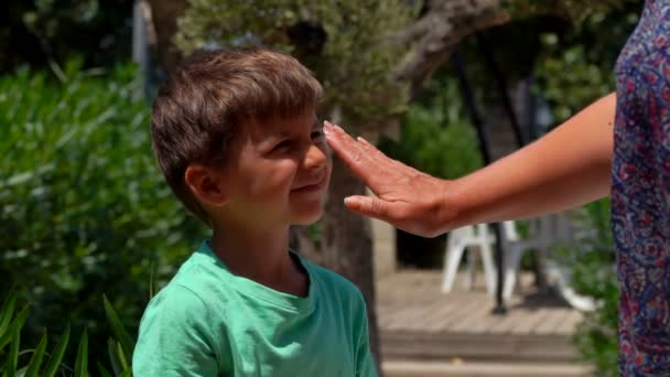 Hand uitstrijkjes beschermende crème op het gezicht van een jongen — Stockvideo