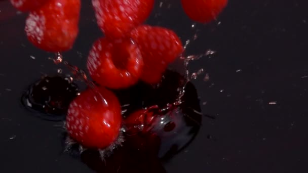 Framboises rouges mûres tombent dans le jus — Video