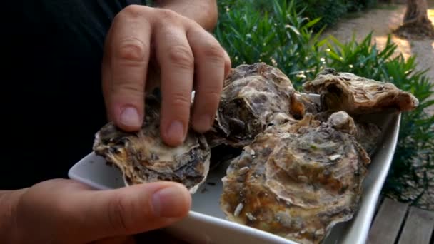 El hombre recoge una ostra en un plato blanco — Vídeos de Stock